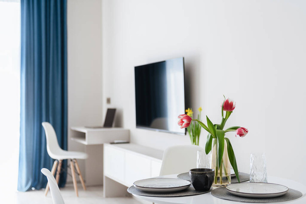 uma mesa com flores, uma TV e cortinas azuis em uma nova casa - Foto, Imagem