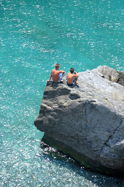 海に見ている岩の上の 2 人の若い男の子の空中写真 - 写真・画像