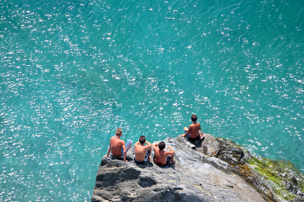 岩で行く日を見て座っている 4 人の若い男の子 - 写真・画像