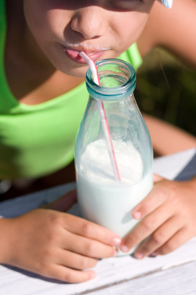 Girl drink milk, focus on big bottle - Foto, Imagem
