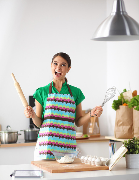 Smiling young woman in the kitchen, isolated on background - Photo, Image