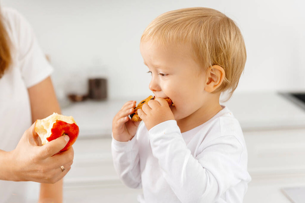 Un niño come galletas y se niega a comer bien y comer sano. Reductor de Comer Disfrutando de Alimentos Vegetales - Foto, imagen