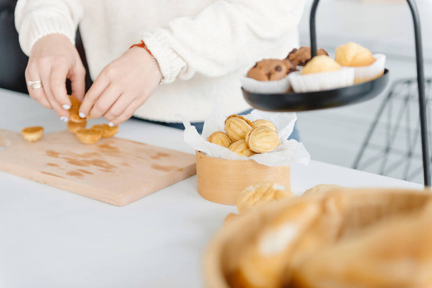 Eine Frauenhand in der modernen Küche bereitet ein Dessert in Form einer Walnuss zu. Geschäft zu Hause. - Foto, Bild