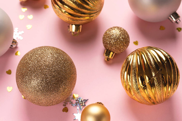 Tarjeta navideña con bolas doradas y plateadas y confeti sobre fondo rosa - Foto, Imagen