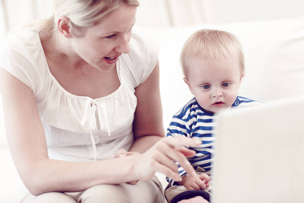 Its never too early to start learning. An attractive young mother showing her curious baby a laptop - Foto, Bild