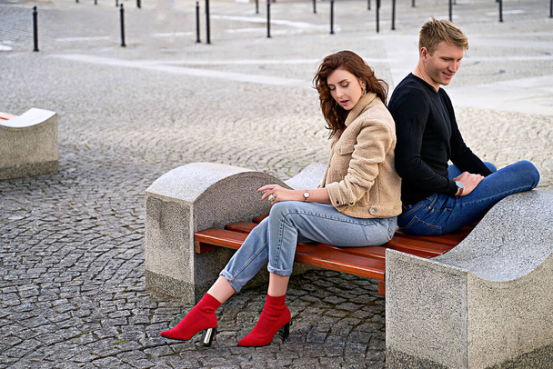 Beautiful young couple sitting on a bench in the city during a romantic date. Urban lifestyle. - Фото, зображення