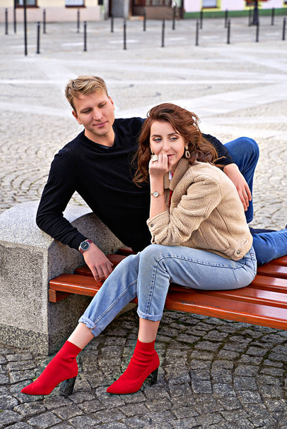 Beautiful young couple sitting on a bench in the city during a romantic date. Urban lifestyle. - Photo, image