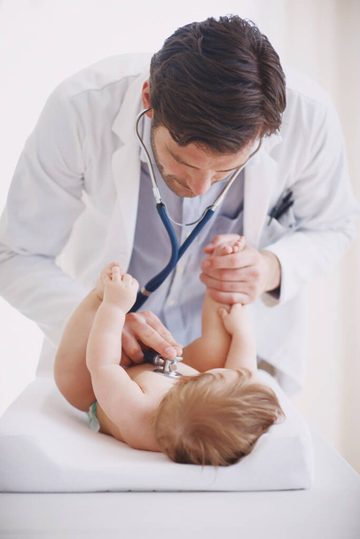 Il travaille si bien avec ses petits patients. Un médecin masculin examine une petite fille avec son stéthoscope - Photo, image