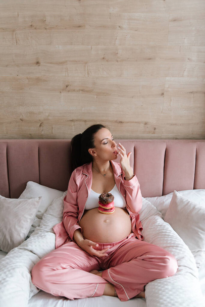 Pregnancy photo session at home, in the kitchen, in the room on the bed, by the window and in the bathroom, brushing your teeth, putting your hands on your tummy and making cheesecakes from flour - Foto, Imagem