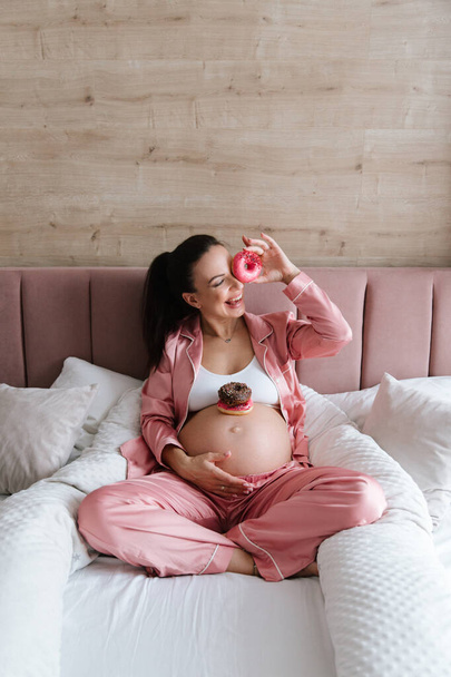 Pregnancy photo session at home, in the kitchen, in the room on the bed, by the window and in the bathroom, brushing your teeth, putting your hands on your tummy and making cheesecakes from flour - Foto, Bild