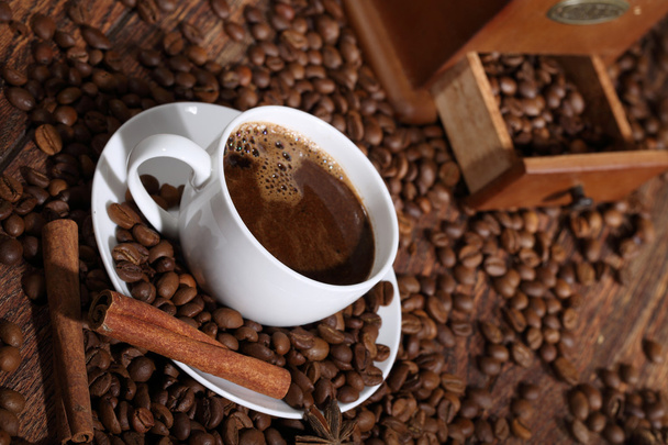 Кава в білій чашці в середовищі кавових зерен, кориця
 - Фото, зображення