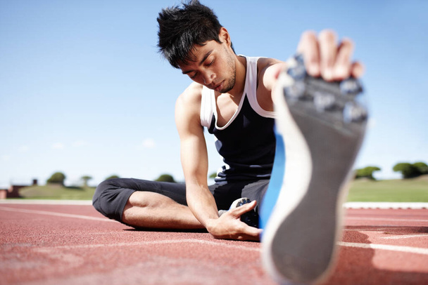 El estiramiento es theraputic. Un joven corredor relajándose mientras se estira - Foto, Imagen