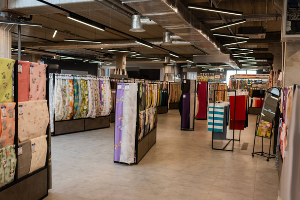 racks with assortment of different fabric material on shelves in textile shop - Фото, зображення