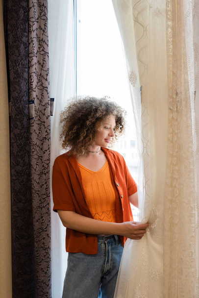 young and curly woman choosing curtains in textile shop - Foto, Bild