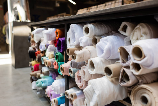 Различные рулоны ткани на полках в текстильном магазине  - Фото, изображение