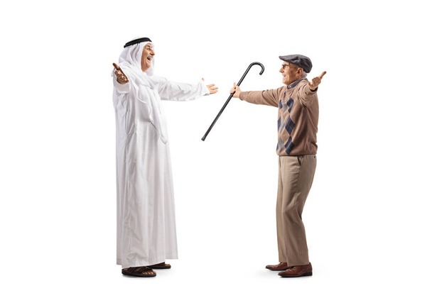 Full length profile shot of a mature arab man in a robe meeting an elderly man isolated on white background - Photo, image