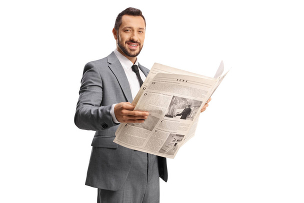 Businessman in a grey suit holding a newspaper and looking at camera isolated on white background - Фото, зображення
