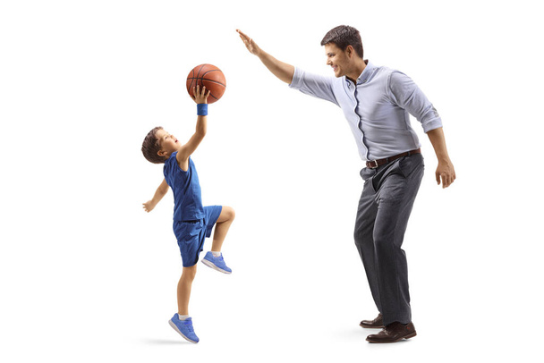 Full length profile shot of a father and son playing basketball isolated on white background - Foto, imagen