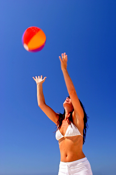 girl beach bal vangen op zonnige strand in Spanje met blauwe hemel - Foto, afbeelding