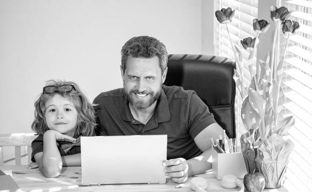 ώριμος άντρας δάσκαλος ή μπαμπάς που βοηθά το παιδί γιο με σχολική εργασία στον υπολογιστή, σχολείο. - Φωτογραφία, εικόνα