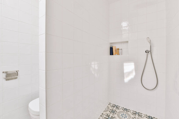 Flush toilet located between sink and shower in small tiled bathroom of contemporary apartment - Photo, Image