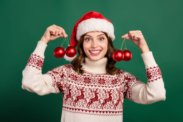 Photo of cheerful pretty lady arms hold xmas tree baubles toys toothy smile isolated on green color background. - Фото, зображення