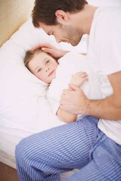 She loves it when dad puts her to bed. A dad lovingly putting his daughter to bed - Foto, Imagen