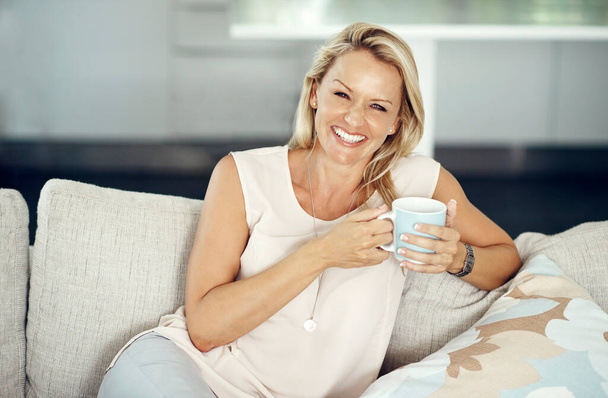 Hyvät päivät alkavat hienolla kahvilla. Rajatut muotokuva houkutteleva kypsä nainen nauttia lämmintä juomaa rentoutuen sohvalla kotona - Valokuva, kuva