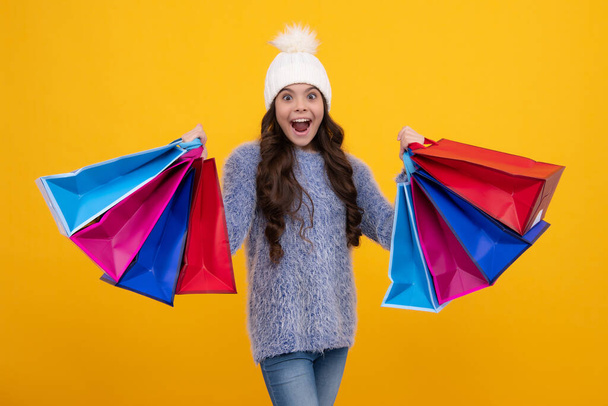Tini gyermek lány télen meleg kalap tartsa bevásárló táska élvezi téli kiárusítás. Őszi vásár. A kislány kész bevásárolni. Izgatott arc, vidám érzelmek a tinédzser lány - Fotó, kép
