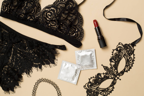 Lace mask, lingerie and condoms on color background, top view. - Foto, afbeelding