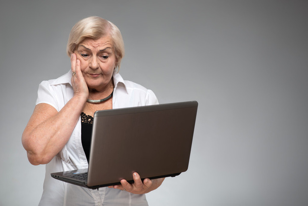 Elderly woman holding the laptop - Fotó, kép
