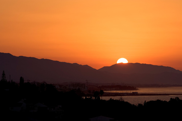 Salida del sol dorada sobre el puerto de Marbella
 - Foto, imagen