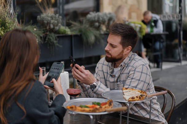 レストランに座って、スマートフォンでテキストメッセージ。ボーイフレンド,日付の携帯電話の閲覧のガールフレンド - 写真・画像