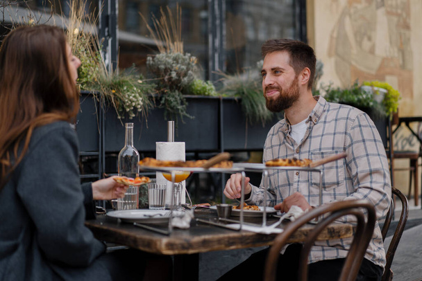 Date - Man and woman are sitting on the terrace of restaurant, pizza, cocktails - Photo, Image