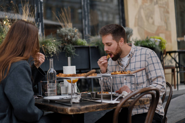 Fecha - Hombre y mujer están sentados en la terraza del restaurante, pizza, cócteles - Foto, imagen