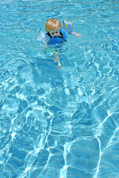プールで泳ぐことを学ぶ若い男の子 - 写真・画像