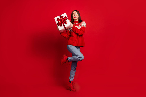 Full size portrait of excited positive girl hands hold festive giftbox look empty space isolated on red color background. - Φωτογραφία, εικόνα