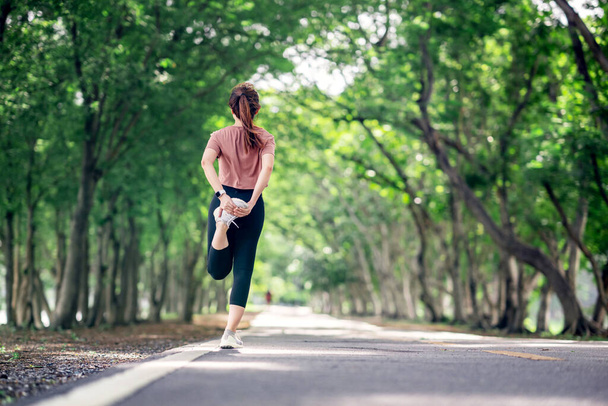 Runner vrouw stretching legs before running in the park, gezonde levensstijl en sport concepten, Warm up, kopieer ruimte. - Foto, afbeelding