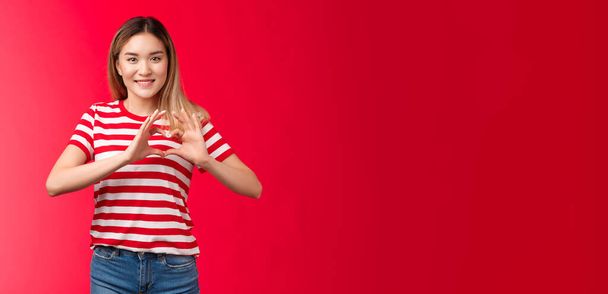 Asian girl express love and support lgbtq community. Heartwarming sweet tender blond female show heart sign near chest smiling friendly happily showing romantic attitude cherish relationship. - Фото, зображення
