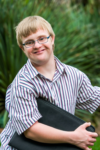 Joven estudiante con síndrome de Down sosteniendo archivos al aire libre
. - Foto, imagen