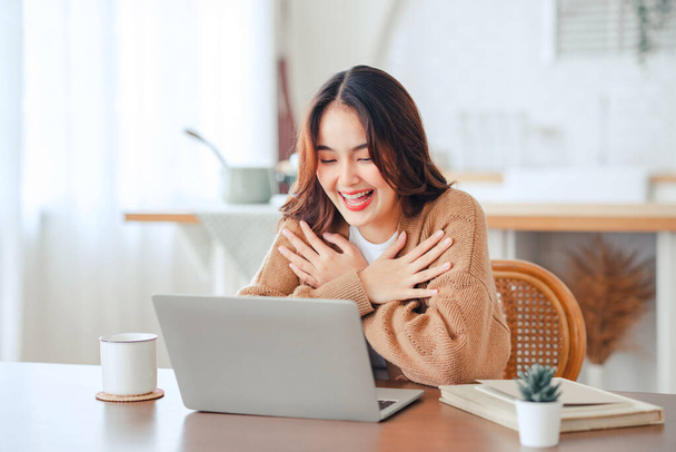 Happy positive young asian woman enjoying online communication at home, Female using wifi while video conferencing with friend, sitting in front of open laptop. - Foto, immagini