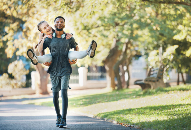 Interracial couple, piggy back and outdoor with smile for fitness, health and exercise in park. Runner, black man and woman on back in workout, running or wellness in urban sunshine by trees together. - Photo, Image