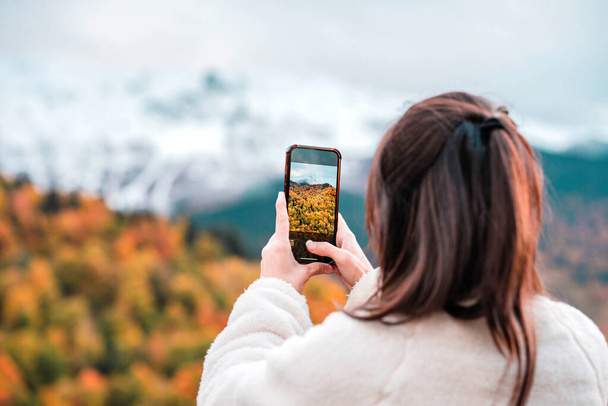 Happy tourist woman taking photo with smart phone on top of mountain in spring or autumn - Photo, Image