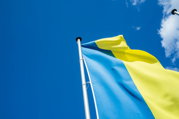 Прапор України на тлі синього неба з хмарами. Державний символ. Вид знизу. - Фото, зображення