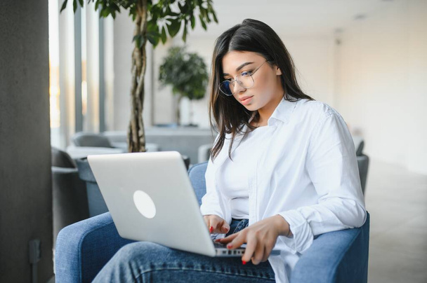 Freelance, business and e-commerce concept. Creative enthusiastic female journalist writing new article, typing on laptop, smiling, write-down project ideas, sit cafe, drink coffee working remote. - Photo, image