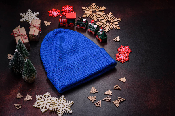 Синя в'язана тепла шапка на темно-коричневому бетонному фоні. Одяг для холодної пори року
 - Фото, зображення