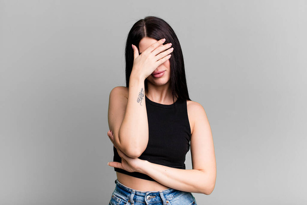 young adult pretty woman looking stressed, ashamed or upset, with a headache, covering face with hand - Photo, image