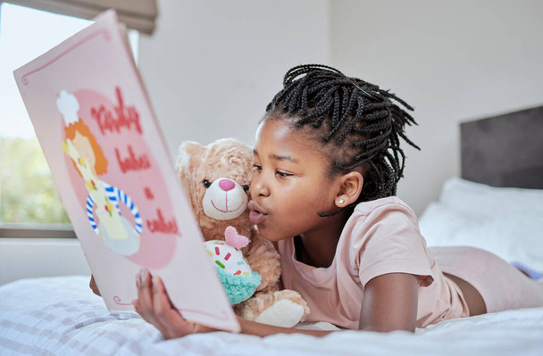 Διάβασμα, βιβλίο και αρκουδάκι με ένα μαύρο κορίτσι στο κρεβάτι, ξαπλωμένη για να χαλαρώσει στην κρεβατοκάμαρα με το χόμπι της. Παιδιά, βιβλία και εκπαίδευση με ένα θηλυκό παιδί να της λέει μια ιστορία στο σπίτι της.. - Φωτογραφία, εικόνα