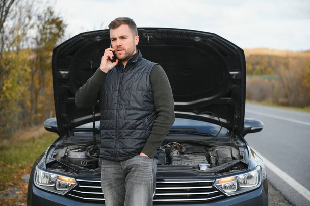 A man calls a phone number to talk to a mechanic. The car broke down on the roadside. The concept for fix, help, problem, repair. blurred background - Foto, immagini