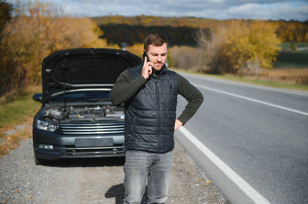 A man calls a phone number to talk to a mechanic. The car broke down on the roadside. The concept for fix, help, problem, repair. blurred background - Foto, imagen
